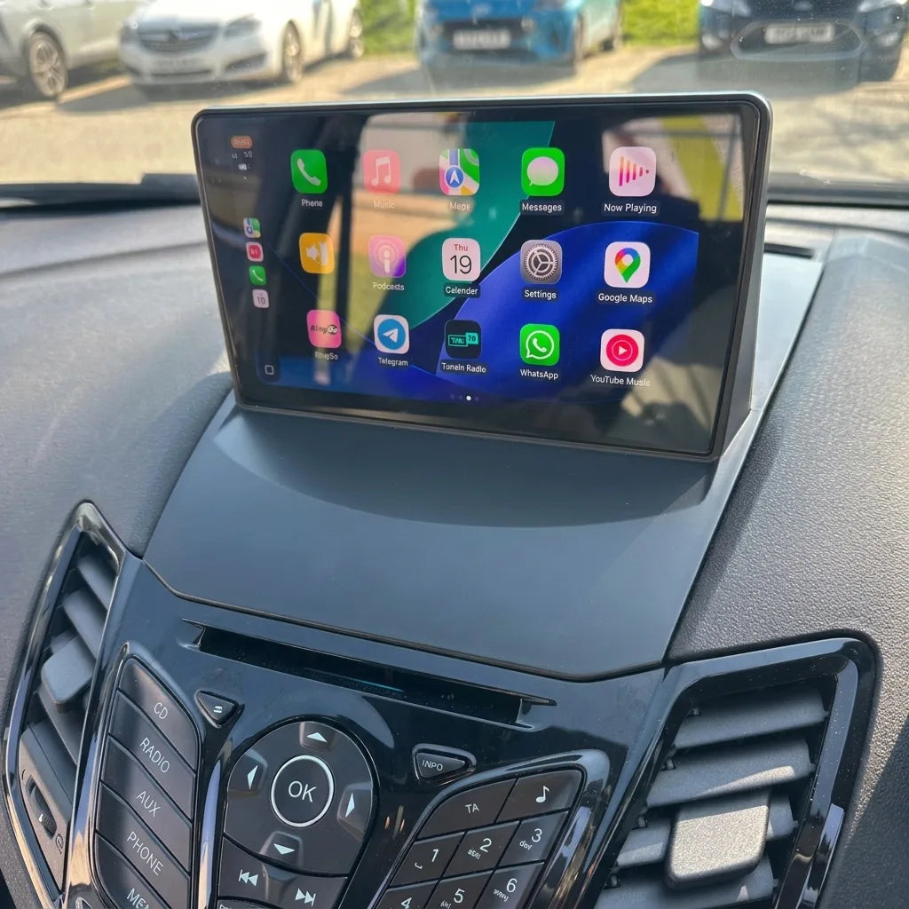 Autoradio CarPlay 9 pouces installé au sommet de la console d'une Ford Fiesta MK7 (2008-2017), clavier Ford d'origine conservé, interface Apple CarPlay