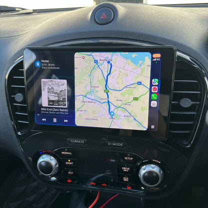 Autoradio CarPlay 9 pouces installé dans la console d'un Nissan Juke F15, entre les aérateurs ronds, commandes de climatisation d'origine conservées
