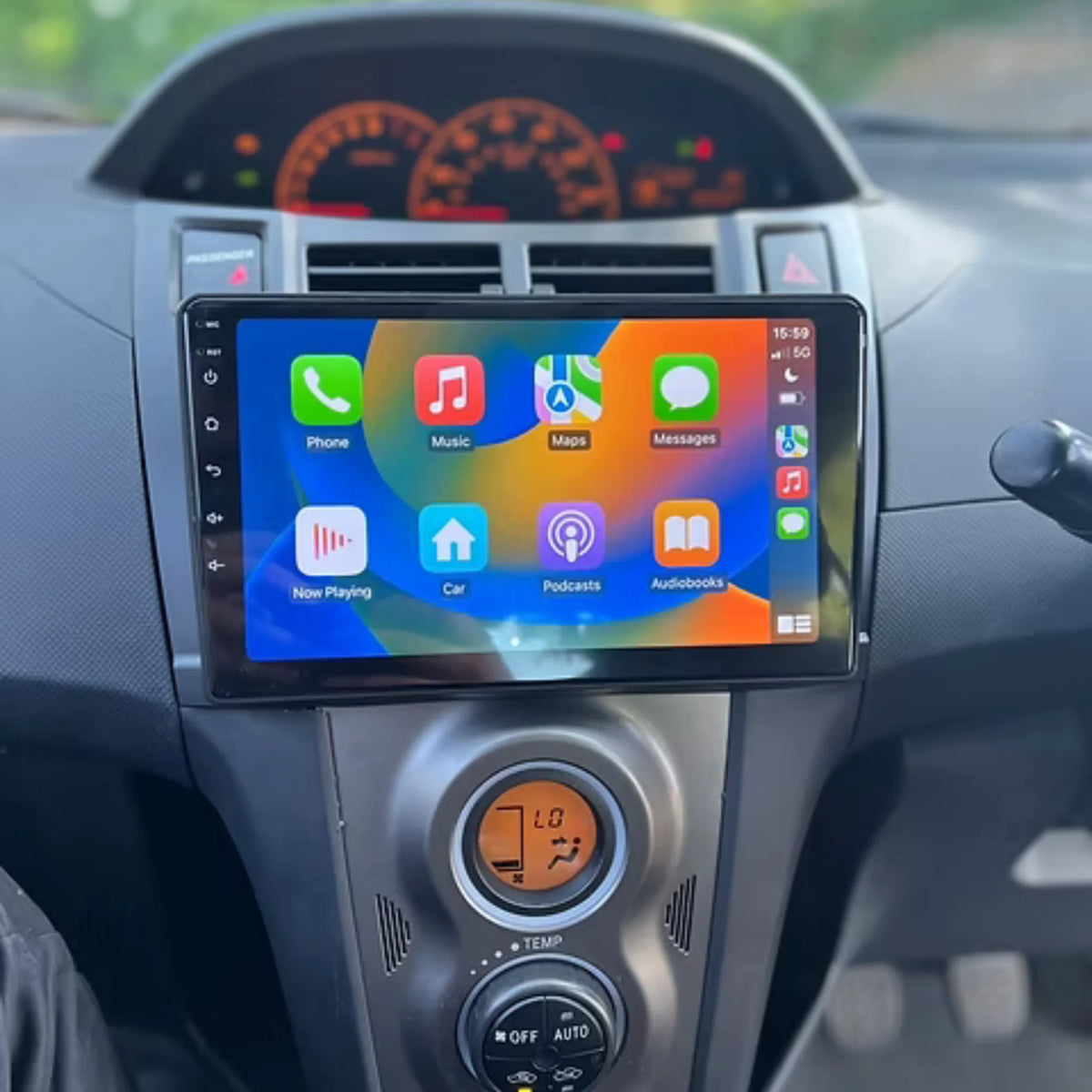 Autoradio CarPlay 9 pouces installé dans la console d'une Toyota Yaris 2 (2005-2011), sous le compteur central, climatisation d'origine conservée